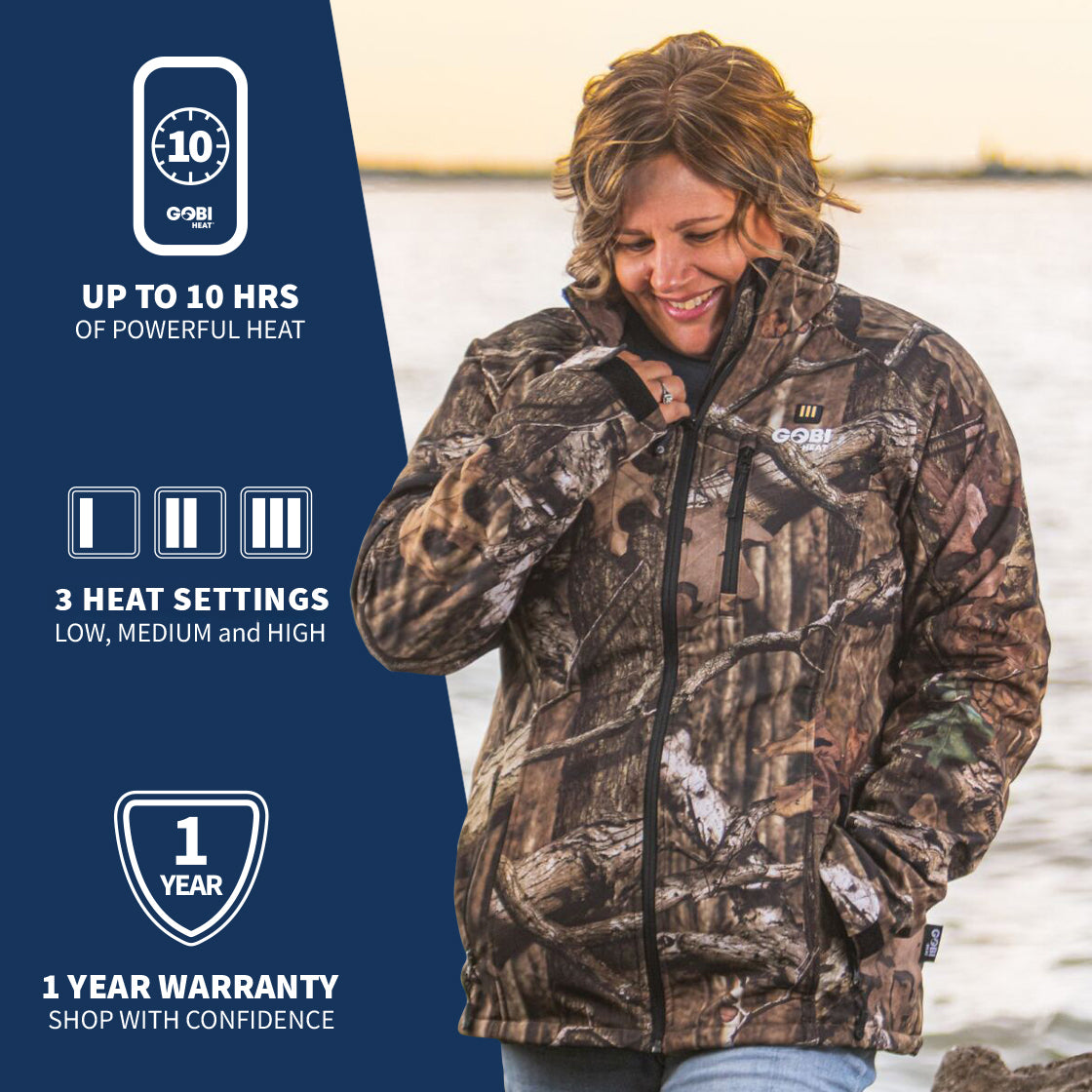 A woman wearing GOBI's women's sahara heated jacket. She is standing in front of a landscape, with information about the product on the left side of the image.